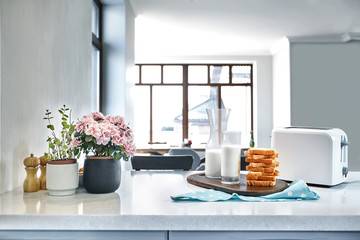 A glass of milk and toast on a table, kitchen background.
