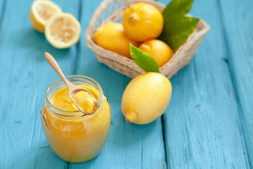 Naklejka na ściany i meble Homemade fresh lemon curd in jar with sliced lemon fruits on wooden board, selective focus