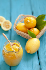 Homemade fresh lemon curd in jar with sliced lemon fruits on wooden board, selective focus
