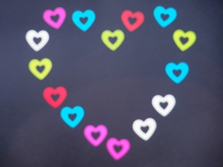 Heart, lined with colorful shiny hearts. Photo on a black background. Blurred image.
