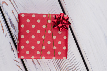 Christmas gift wrapped in red dotted paper. Present box wrapped in patterned paper and tied with...
