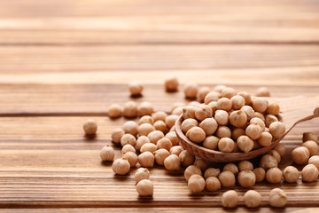 Chickpeas in spoon on brown wooden table