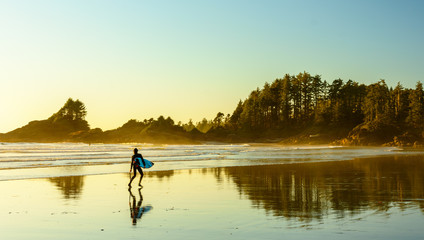 Ein Surfer geht an einem Strand auf Vancouver Island entlang