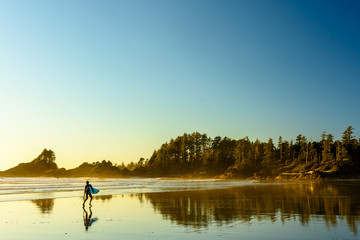 Ein Surfer geht an einem Strand auf Vancouver Island entlang