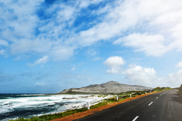 coastal road on cape peninsula near Cape Town against rough sea and blue sky