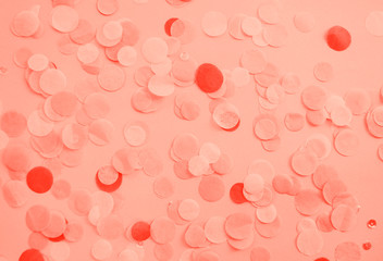 Flat lay of living coral color confetti and sparkles on pink background. Color of the year 2019 concept.
