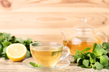 Cup of tea with mint leafs on wooden table