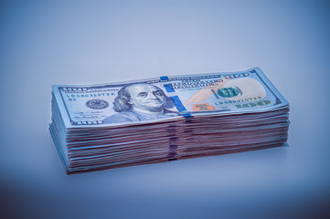 A big stack of hundred-dollar bills. Blue design. Vignetting.