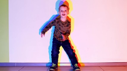 Happy kid boy having fun and dancing in colorful lights. Emotional smiling cheerful little child playing with parents in entertainment game center on holidays. 