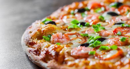 Pizza with Mozzarella cheese, olives, shrimps, tomato sauce, Spices and Fresh green onion. Italian pizza on wooden table background