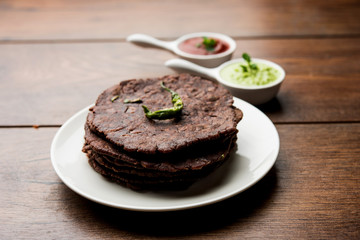 Ragi roti or flat Bread made using finger millet is a healthy and tasty breakfast dish of Karnataka, India. served with green chilli and chutney. selective focus