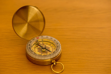 A golden compass on a wooden table