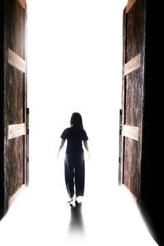 Woman Walking Into The Light Through Open Big Door 