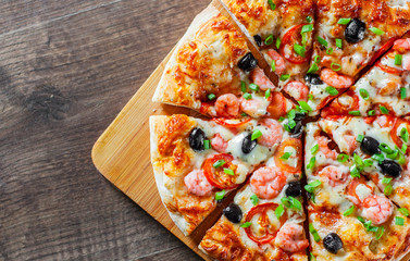 Pizza with Mozzarella cheese, olives, shrimps, tomato sauce, Spices and Fresh green onion. Italian pizza on wooden table background
