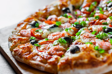 Pizza with Mozzarella cheese, olives, shrimps, tomato sauce, Spices and Fresh green onion. Italian pizza on wooden table background