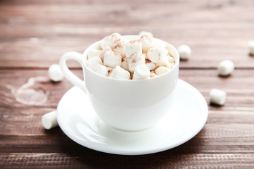 Cappuccino with marshmallows in cup on brown wooden table