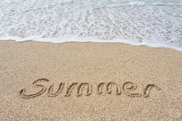 Summer inscription on a tropical sandy beach with blue sea, waves and foam on a background.
