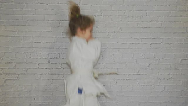 a girl, a child in a kimono on karate training works out blows and greeting
