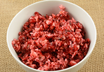 Chopped fresh raw cranberries in white bowl as ingredient for making Thanksgiving or Christmas dishes