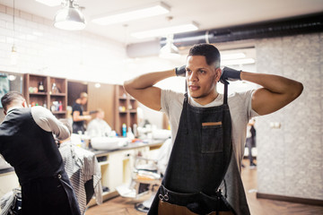 Fototapeta na wymiar Young hispanic haidresser and hairstylist standing in barber shop.