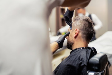 A man client visiting haidresser and hairstylist in barber shop.