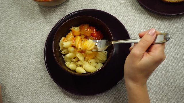The process of eating pasta with lecho sauce.