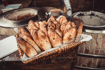 Baker making turkish pita bread in tandoor (clay oven). Baking process. Many fresh hot bread in the basket