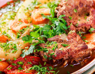 Baked meat with grilled vegetables, potatoes, greens in plate on wooden background. Hot Meat Dishes