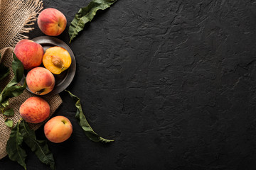 Ripe peaches on black stone background. Healthy food concept, top view, copy space