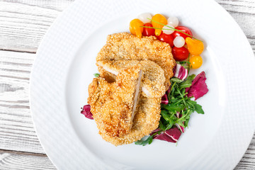 Grilled chicken breasts with sesame, salad with cabbage fat and rucola on light wooden background. Hot Meat Dishes
