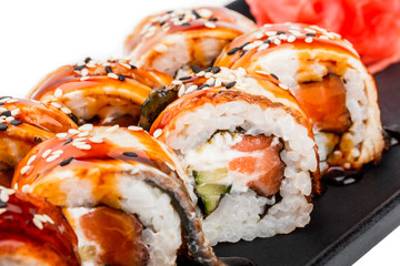 Sushi Roll - Maki Sushi made of salmon, smoked eel, cucumber, avocado and cream cheese on black plate isolated over white background. Japanese cuisine