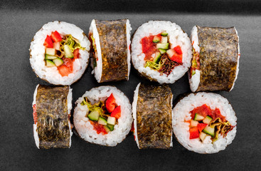 Sushi Roll - Maki Sushi with pepper, cucumber, tomato and cabbage on black plate isolated over white background. Japanese cuisine. Vegan food concept. Top view