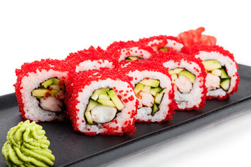 Sushi Roll - Maki Sushi with red caviar, Crab meat, cucumber, avocado on black plate isolated over white background. Japanese cuisine