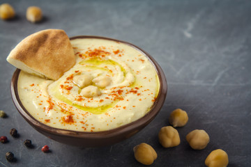 Hummus plate and pita bread on dark background. Mediterranean snack, vegetarian healthy food...