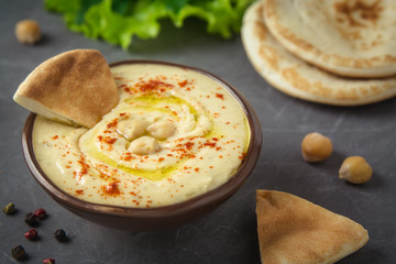 Chickpea hummus bowl and pita bread on grey background. Mediterranean snack, vegetarian healthy...