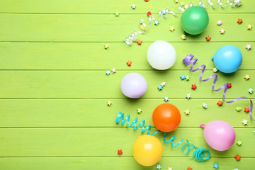 Colorful balloons with paper stars on green wooden table