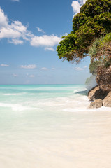 Pacific waves on a summer day stumble upon a snow-white rocky beach of the African continent against a blue sky.