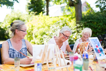 Happy elderly women attending an outdoor art class.