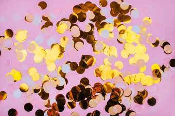Vibrant gold confetti on pastel pink background. Festive design.