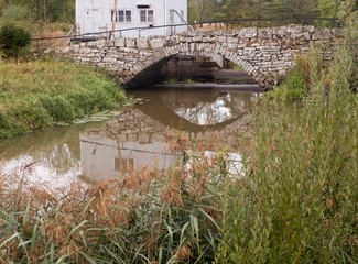 Eine alte Brücke aus Bruchstein spiegelt sich in den kleinen Fluss,  gesehen bei Lidköping in...