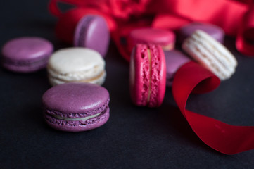 macaroon on black background with red ribbon, colorful almond cookies, pastel colors.