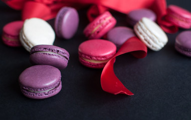 macaroon on black background with red ribbon, colorful almond cookies, pastel colors.