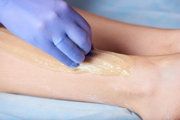 Naklejka premium Hair removal method sugaring on legs in a beauty salon