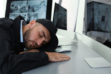 Male security guard sleeping at workplace indoors