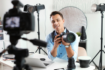 Male photo blogger recording video on camera indoors