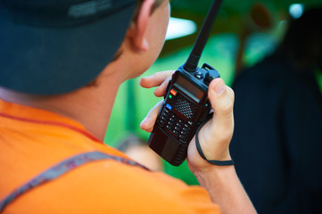 A man with a black portable radio tranciever or walkie-talkie