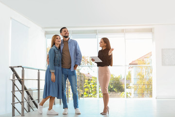 Female real estate agent showing new house to couple, indoors