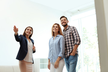 Female real estate agent showing new house to couple, indoors