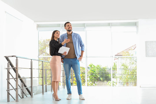 Female real estate agent showing new house to man, indoors
