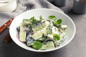 Plate with creamy cucumber salad served on table